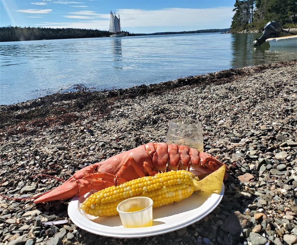 Steamed lobster and corn on plate with sailboat on the background.