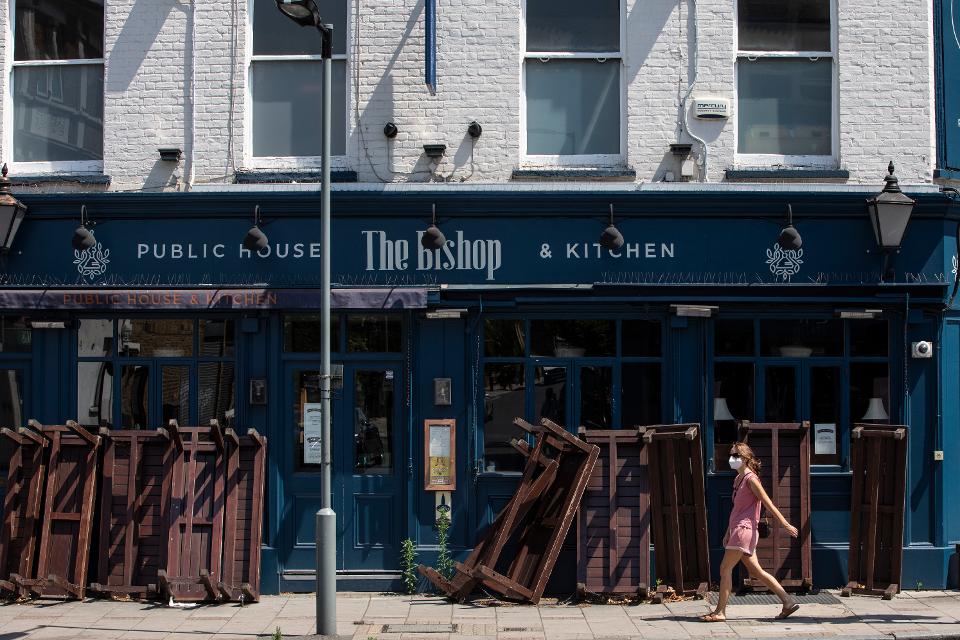 A woman wearing a face mask walks past a closed pub in Dulwich on June 24, 2020 in London, England.