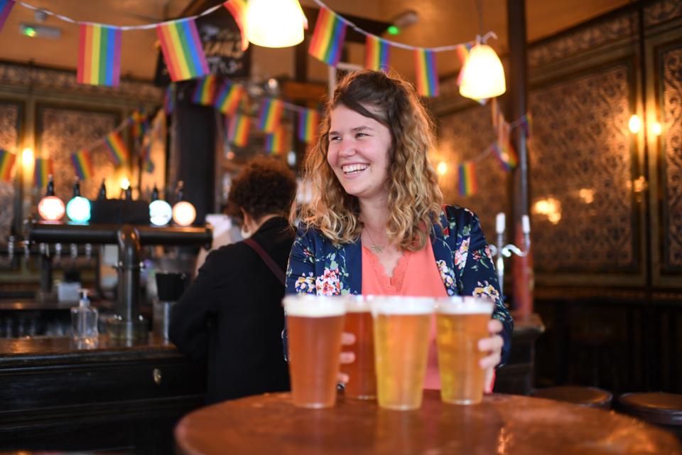 Customers leave with pints of beer for takeaway at The Ten Bells pub in east London on June 27, 2020.